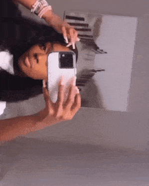 a woman is taking a picture of herself in a mirror with a cell phone .