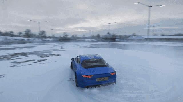 a blue sports car is driving through a snowy field