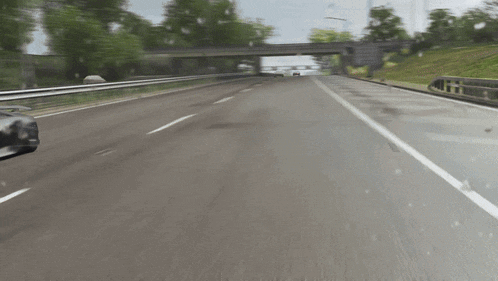a car is driving down a highway with trees on both sides