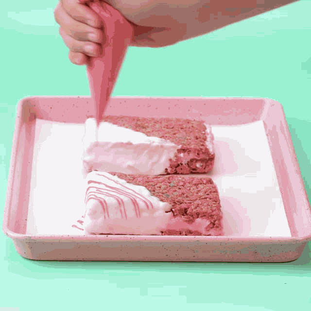 a person is frosting a cake with pink frosting on a pink pan