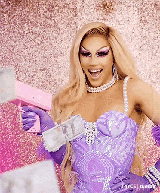 a drag queen in a purple dress and gloves is holding a gun with money in it .