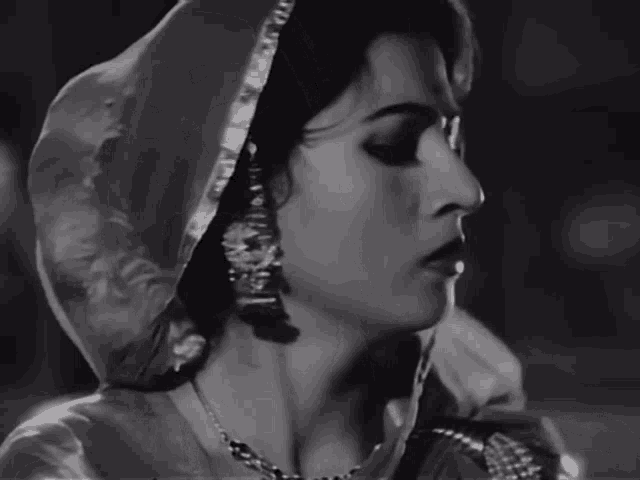 a black and white photo of a woman wearing a veil and earrings