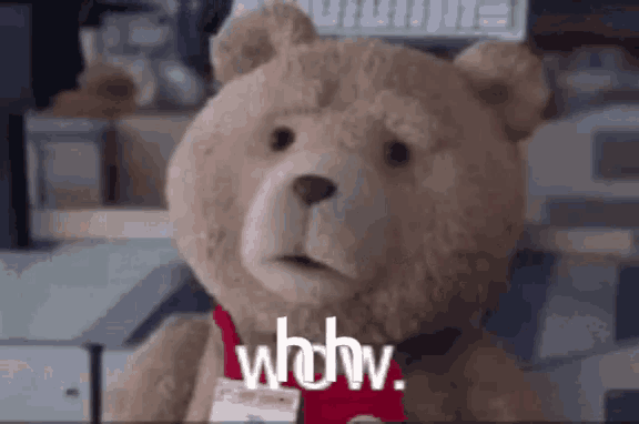 a teddy bear wearing a name tag and a red tie is talking .