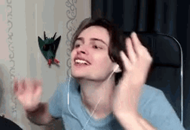 a young man wearing headphones is smiling and making a funny face .