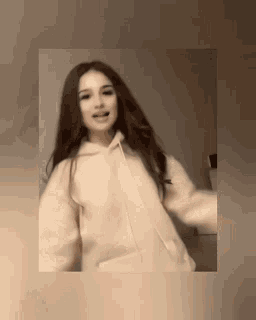 a woman in a hoodie is dancing in a room .