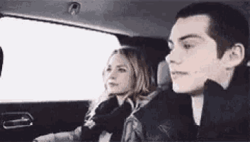 a man and a woman are sitting in the back seat of a car looking out the window .