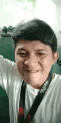 a young man is taking a selfie and smiling while wearing a lanyard .
