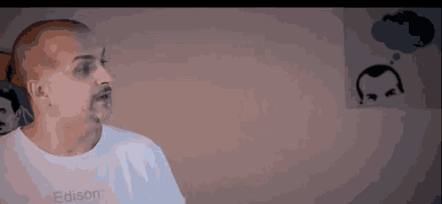 a bald man with a beard is wearing a white t-shirt that says edison on it .