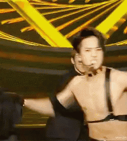 a man without a shirt is dancing on a stage