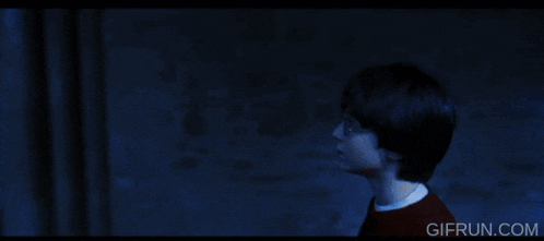 a man in a red sweater is standing in a dark room with a giflin.com logo in the corner