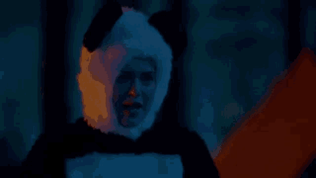 a woman in a panda costume is standing in the dark in front of a fire .