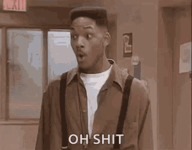 a man in a brown shirt and suspenders is standing in a room with his mouth open and says `` oh shit '' .