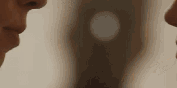 a close up of two people 's faces looking at each other in a mirror .