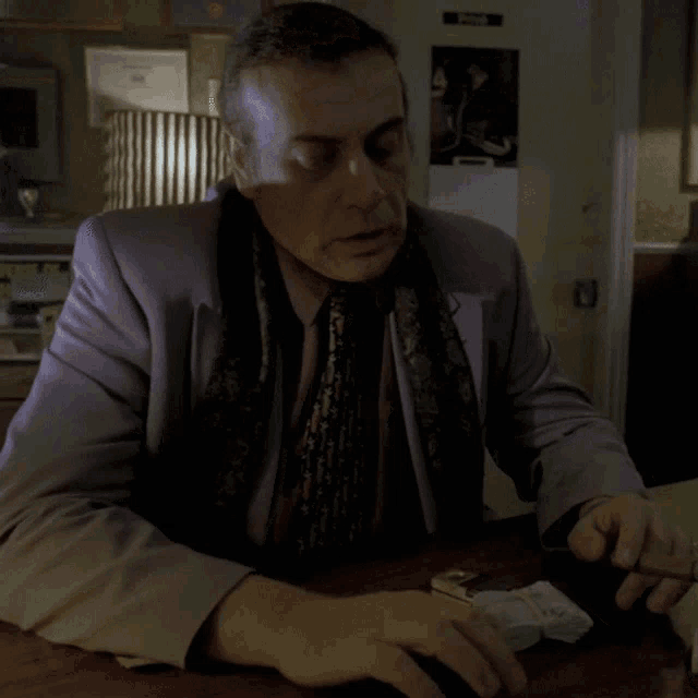 a man in a suit and tie is sitting at a table with the word quoi written on his arm
