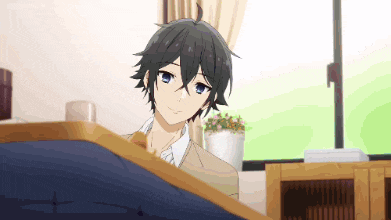 a boy is sitting on a bed in a room with a potted plant in the background .