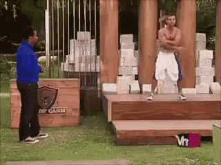 a man in a blue jacket is standing next to a man in white shorts on a stage with a sign that says vh1