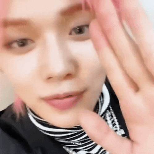 a close up of a person 's face with pink hair wearing a black and white striped shirt .