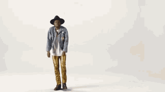 a man wearing a hat and gold pants is dancing in front of the word hey