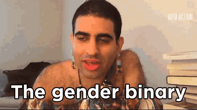 a man is talking about the gender binary in front of a pile of books