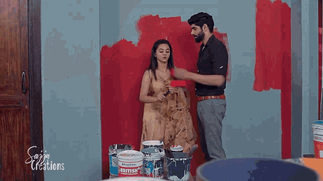 a man and a woman are painting a wall with a bucket of babyish paint