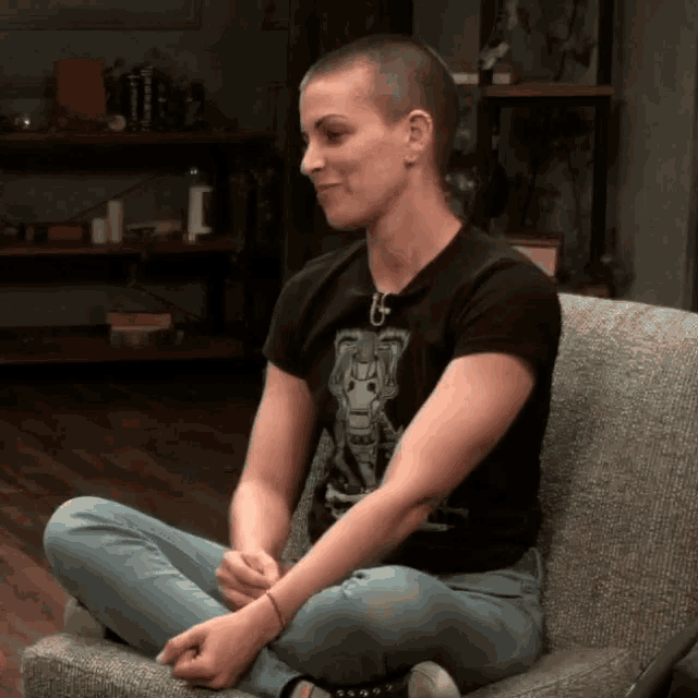 a woman with a shaved head is sitting on a chair