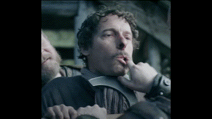 a man with curly hair is holding his finger to his lips