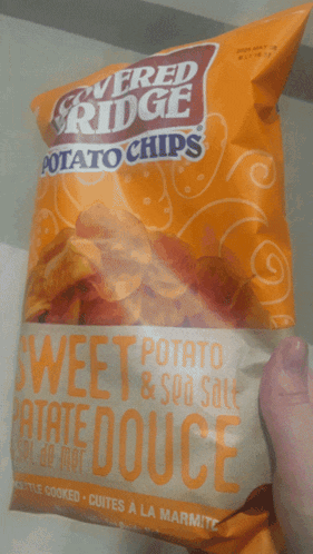 someone is holding a bag of sweet potato chips