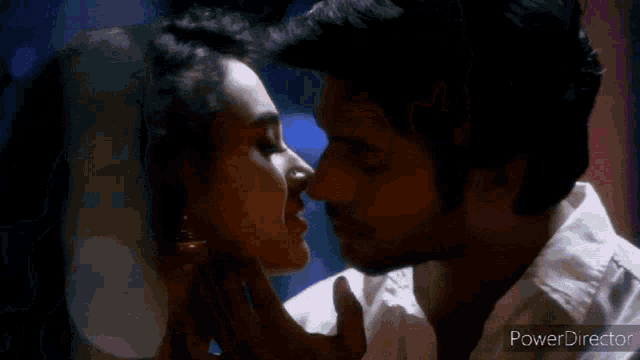 a man and a woman are kissing in front of candles in a room .