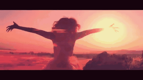 a woman is standing on top of a hill with her arms outstretched .
