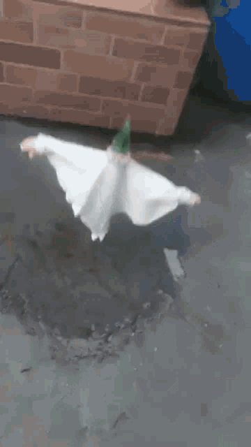 a scarecrow is sitting on a brick wall next to a bucket .