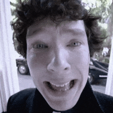 a man with curly hair is making a funny face with his mouth wide open .