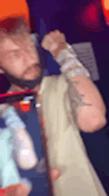a man with a beard and tattoos is standing in a dark room .