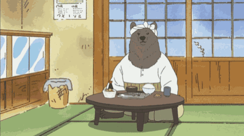 a bear is sitting at a table with a bowl of food