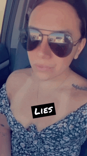 a woman wearing sunglasses has a sticker on her chest that reads lies