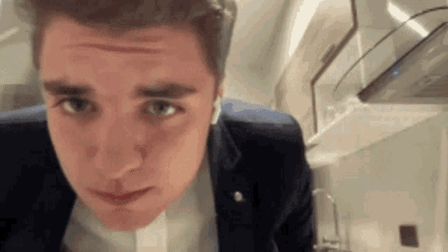 a young man in a suit and ear buds is making a funny face .