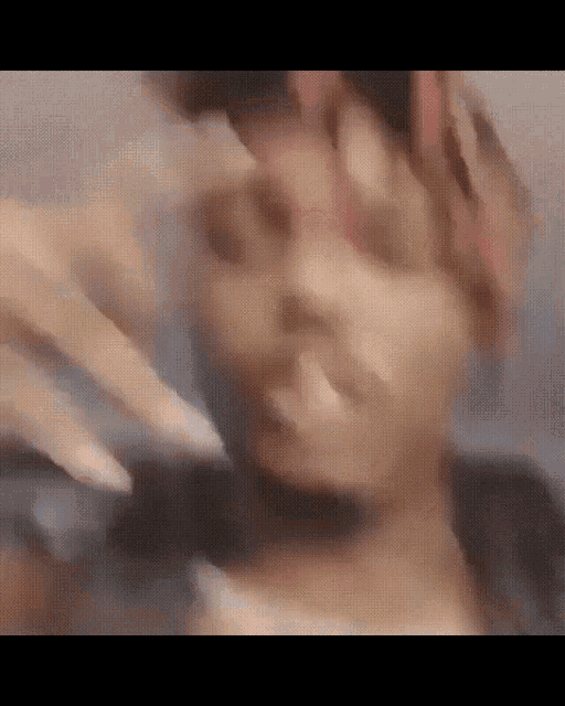 a blurry picture of a person 's face with their hands on it .