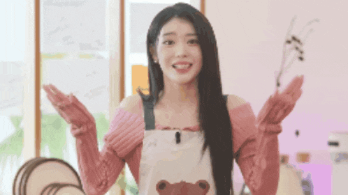 a woman wearing an apron with a teddy bear on it is standing in a room with her arms outstretched .