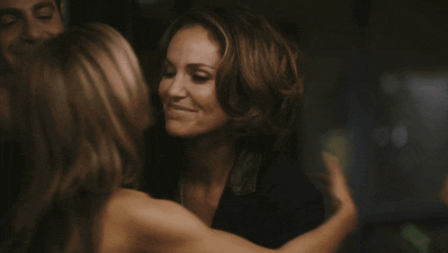 two women are hugging each other and one of them is smiling