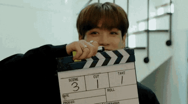 a man is holding a clapper board in front of his face .