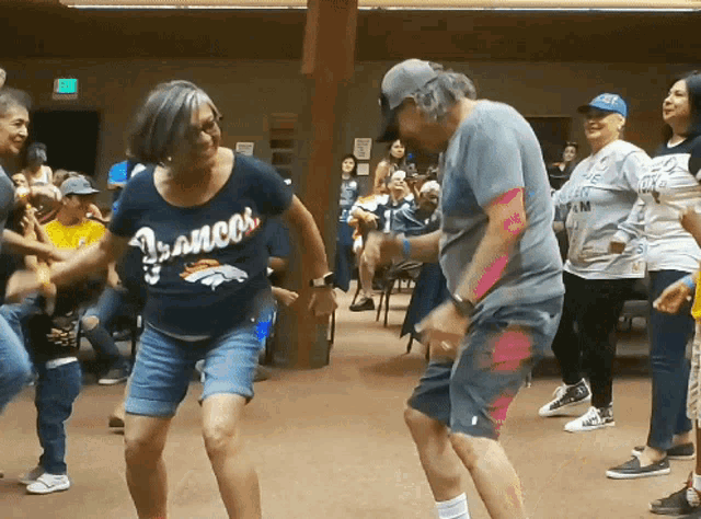a woman wearing a shirt that says " broncos " is dancing