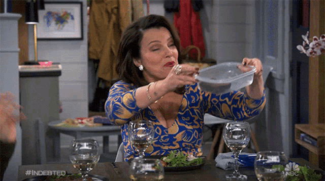 a woman is sitting at a table drinking from a plastic container with the hashtag #indebted on it