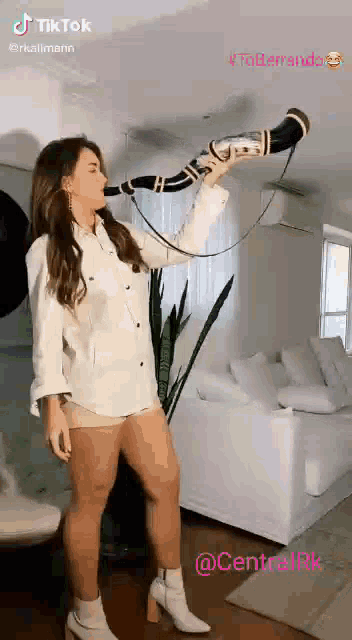 a woman in a white shirt and shorts is blowing a horn .