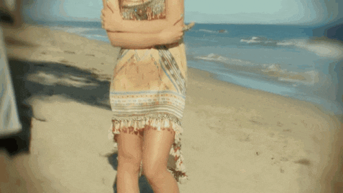 a woman with a crown on her head stands on the beach