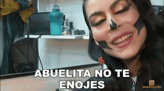 a woman with a skull painted on her face is smiling with abuelita no te enojes written below her