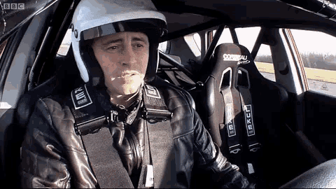 a man wearing a helmet and a leather jacket is sitting in a car with a bbc logo on the bottom right