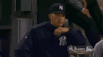 a man wearing a new york yankees hat and sweatshirt is flexing his muscles .