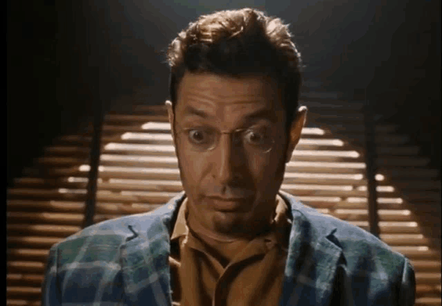 a man wearing glasses and a plaid jacket looks very surprised