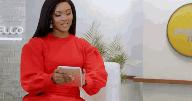 a woman in a red dress is looking at a tablet in front of a sign that says mobile