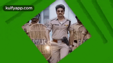 a man in a police uniform is standing next to a group of police officers holding shields .