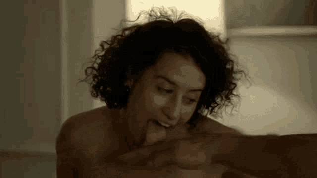 a woman with curly hair is licking a man 's ear .